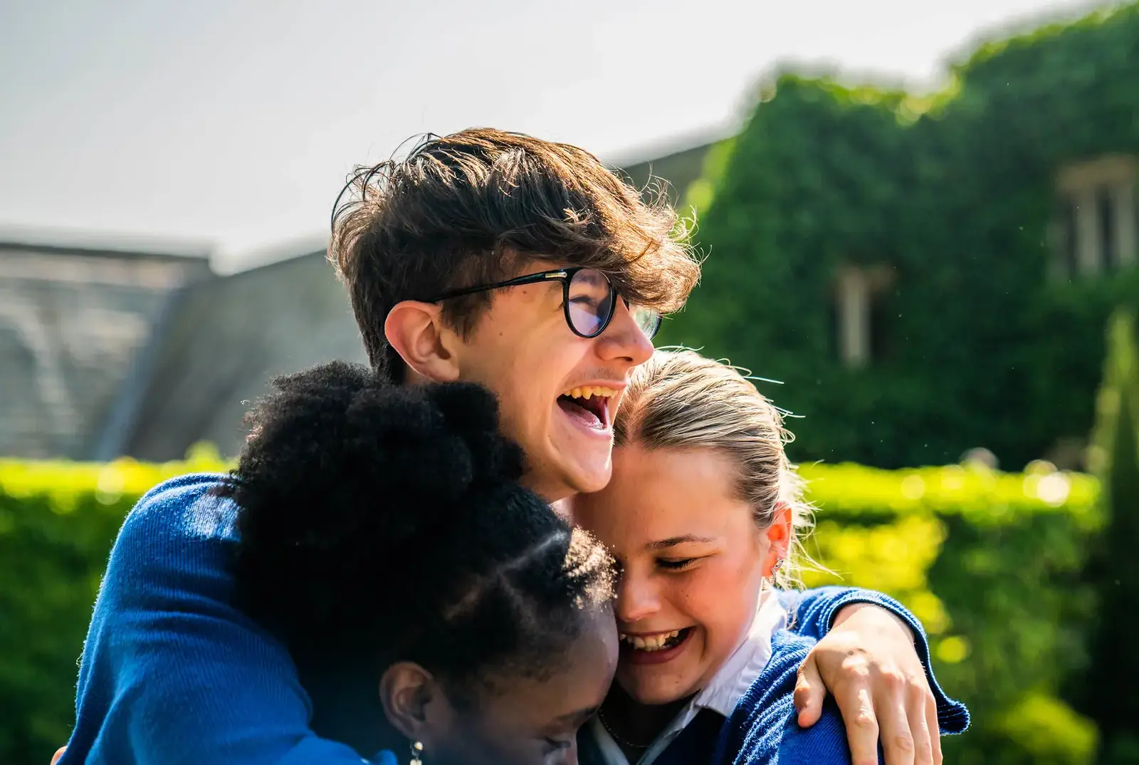 Happy senior school pupils hugging at Queen Ethelburga's