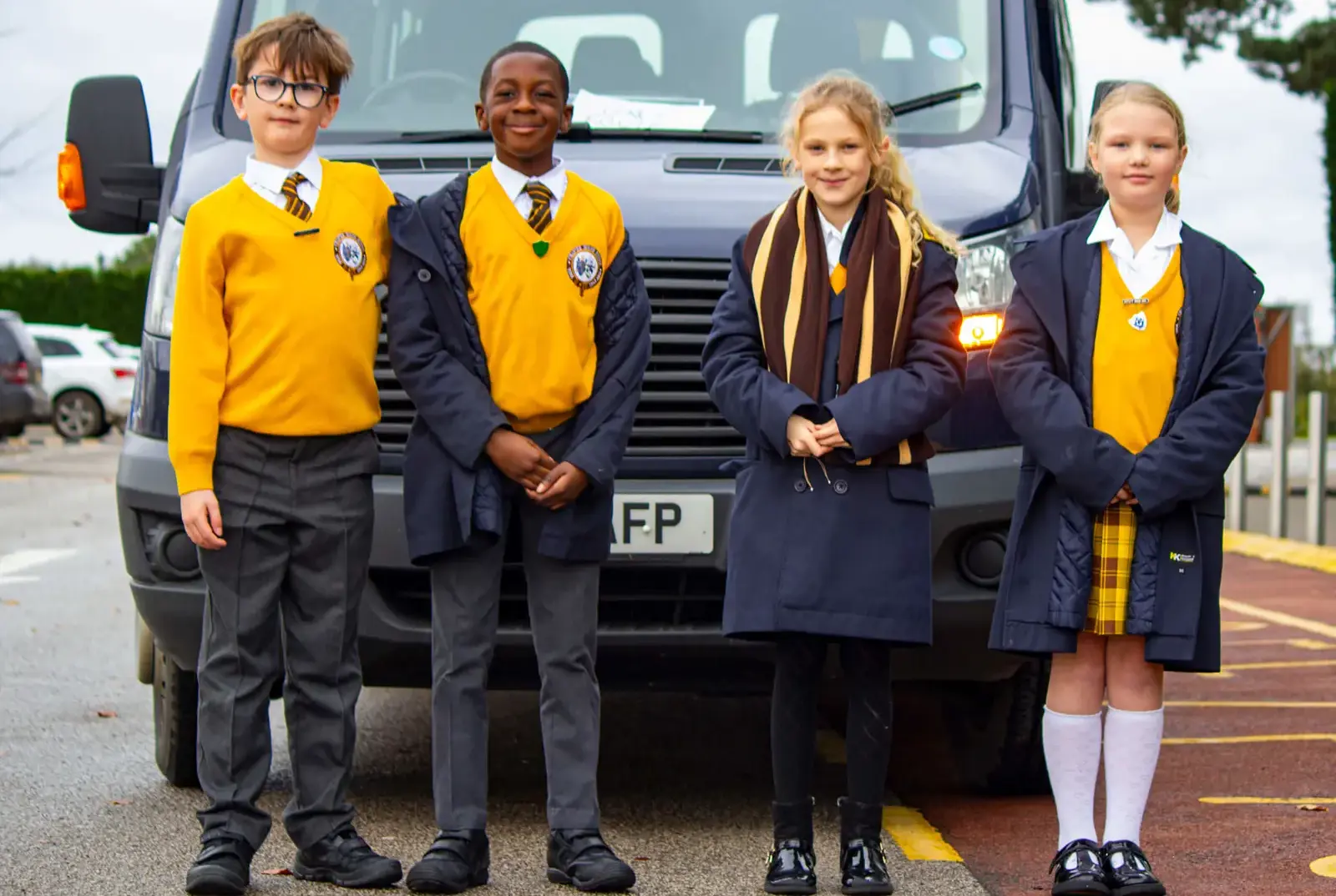 Queen Ethelburga's students in front of a school bus